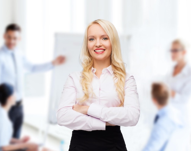 koncepcja biznesu, pracy zespołowej i ludzi - uśmiechnięta kobieta interesu, studentka lub sekretarka nad biurem i grupą kolegów