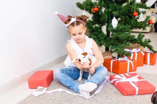 Koncepcja Boże Narodzenie, zwierzęta domowe i święta - dziecko w santa hat z szczeniakiem jack russell terrier.