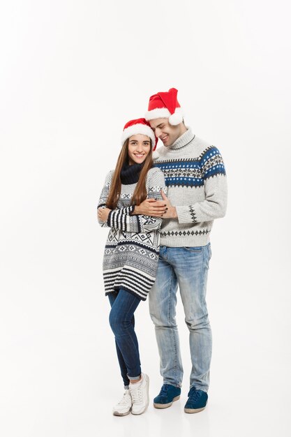 Koncepcja Bożego Narodzenia - pełnej długości Młoda atrakcyjna para kaukaska przytulanie obchodzi Boże Narodzenie.