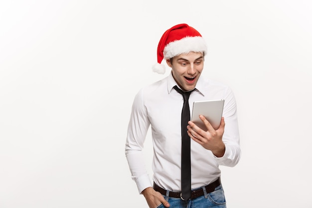 Koncepcja Bożego Narodzenia - Przystojny Biznesmen Nosić Santa Hat Gry Tablet Z Zaskakującym Wyrazem Twarzy.