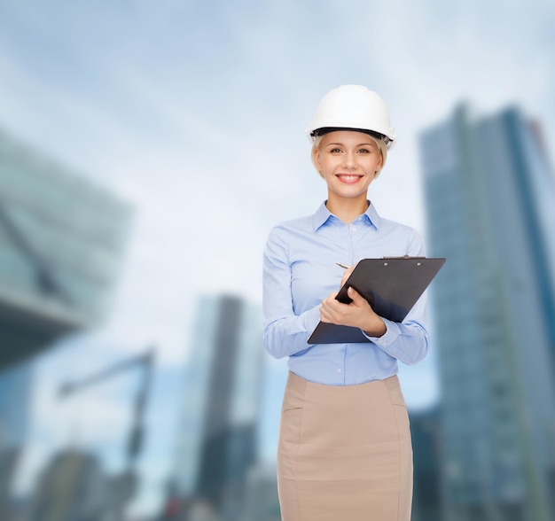 koncepcja budowy, rozwoju, konstrukcji i architektury - uśmiechnięta bizneswoman w białym kasku ze schowkiem