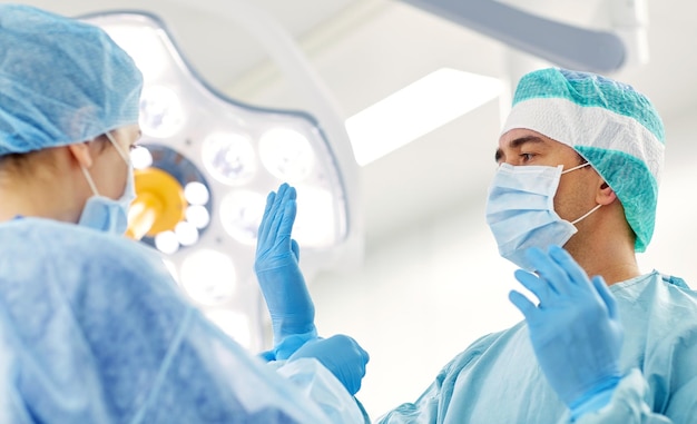 koncepcja chirurgii, medycyny i ludzi - pielęgniarka pomagająca chirurgowi i pomagająca w rękawiczkach na sali operacyjnej w szpitalu