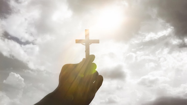 Koncepcja chrześcijaństwa ręka trzymająca krzyż na tle nieba