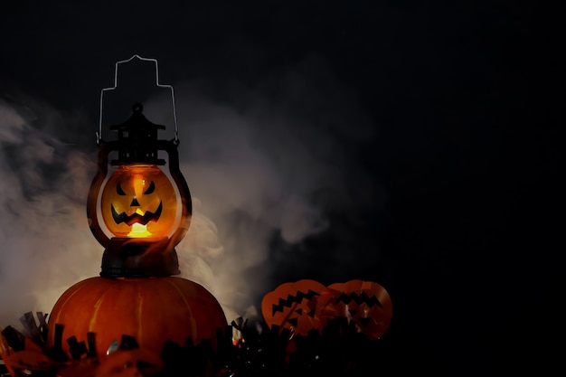 Koncepcja ciemnego tła halloween ze świecącą latarnią i dyniami z dymem