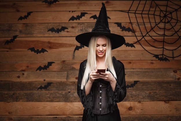 Koncepcja Czarownicy Halloween - Happy Halloween Witch Gospodarstwa Pozowanie Nad Starą Drewnianą ścianą.