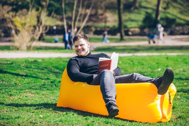 Koncepcja czytania książki mężczyzna w parku miejskim na nadmuchiwanym materacu