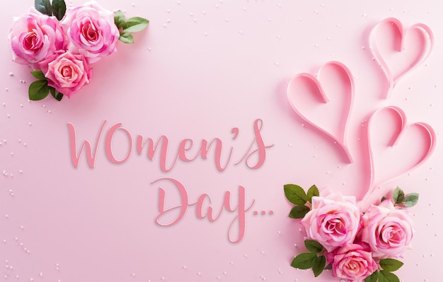 Koncepcja dekoracji Happy Womens Day wykonana z kwiatów róży i różowych serc z tekstem na pastelowym tle