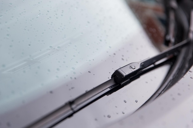 Koncepcja deszczowej pogody i pojazdów - zbliżenie wycieraczki przedniej szyby i mokrego szkła samochodowego