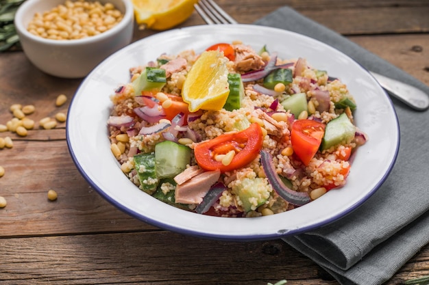 Koncepcja diety dietetycznej Sałatka z tuńczyka Sałatka z kuskusem z konserwowanymi pomidorami z tuńczyka, ogórkami i fioletową cebulą na stole Skopiuj miejsce