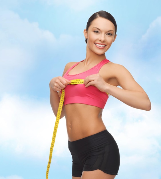 koncepcja diety, zdrowia i ćwiczeń - piękna sportowa kobieta mierząca jej piersi