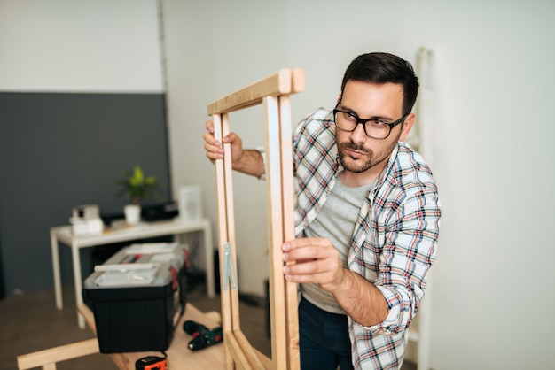 Koncepcja DIY. Młody człowiek montażu drewna tabeli.