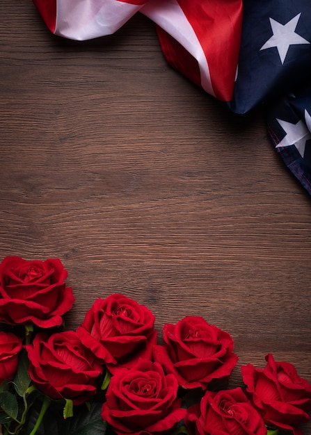 Koncepcja Dnia Niepodległości Stanów Zjednoczonych lub Dnia Pamięci. Flaga narodowa i czerwona róża na tle ciemnego drewnianego stołu.