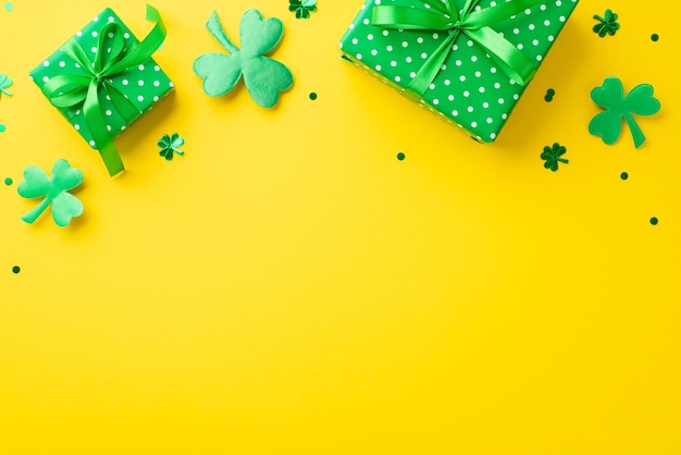 Koncepcja Dnia Świętego Patryka Zdjęcie z górnego widoku zielonych pudełek z prezentami z wstążkami, konfetami w kształcie szamrok i koniczyny na izolowanym żółtym tle z copyspace