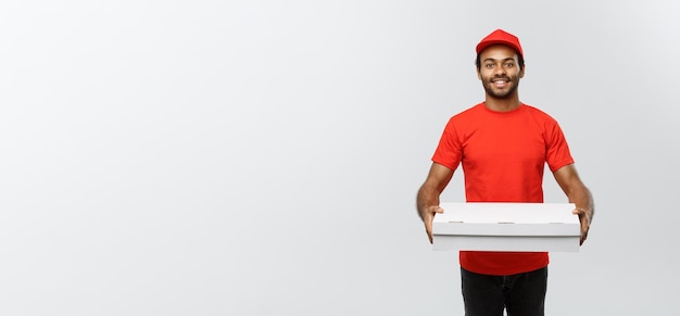 Koncepcja dostawy portret przystojny mężczyzna dostawy pizzy afroamerykańskiej na białym tle na szarym tle studio Kopia przestrzeń