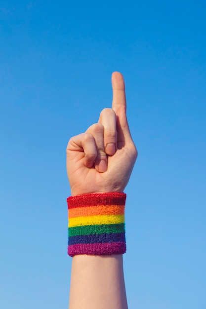 Koncepcja dumy gejowskiej Wskazująca dłoń z opaską z tęczową flagą LGBT na nadgarstku