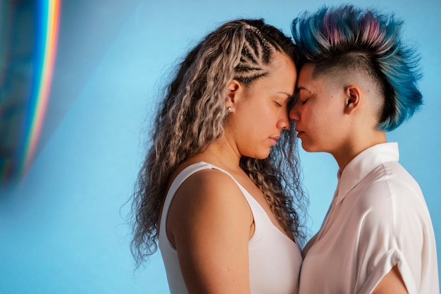 Koncepcja dumy LGBT. Prawdziwa para lesbijek, przytulanie i całowanie z kultowym tęczowym symbolem lgbt.