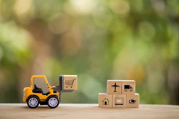 Koncepcja dystrybucji sieci logistycznej i ładunków: Mini wózek widłowy przesuwa paletę z drewnianym klockiem z ikoną. przedstawia dostarczanie towarów lub produktów na całym świecie w e-handlu.