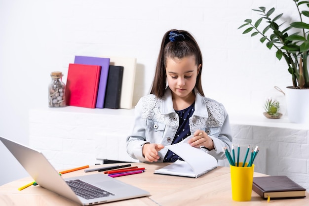 koncepcja dzieci, edukacji i uczenia się na odległość - mała studentka z laptopem w domu