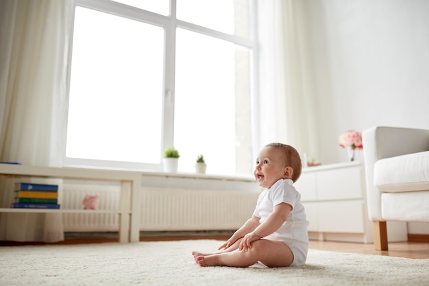 koncepcja dzieciństwa, dzieciństwa i ludzi - szczęśliwy mały chłopiec lub dziewczynka siedzi na podłodze w domu