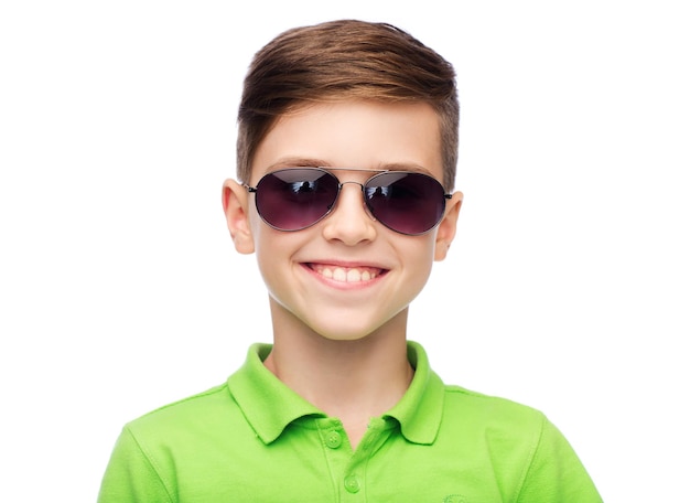 koncepcja dzieciństwa, mody, akcesoriów, stylu i ludzi - szczęśliwy uśmiechnięty chłopiec w okularach przeciwsłonecznych i zielonej koszulce polo