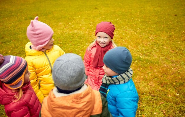 koncepcja dzieciństwa, wypoczynku, przyjaźni i ludzi - grupa szczęśliwych dzieci stojących w kręgu w jesiennym parku