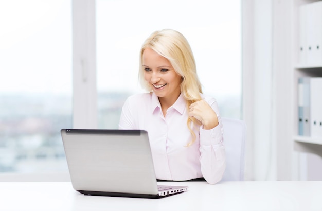 koncepcja edukacji, biznesu i technologii - uśmiechnięta kobieta lub studentka z laptopem w biurze