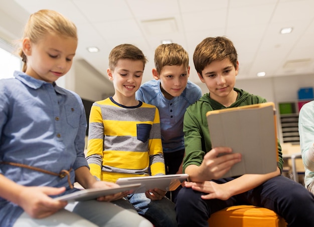 koncepcja edukacji, dzieci, technologii i ludzi - grupa szczęśliwych dzieci z komputerami typu tablet pc uczącymi się w szkole