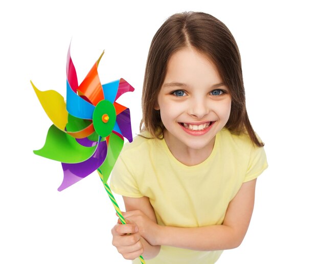 koncepcja edukacji, dzieciństwa i ekologii - uśmiechnięte dziecko z kolorową zabawką z wiatrakiem