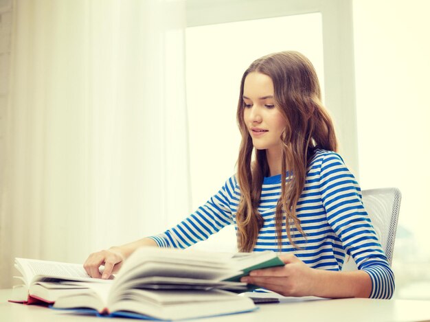 koncepcja edukacji i domu - szczęśliwa uśmiechnięta studentka z książkami