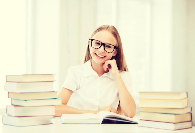 koncepcja edukacji i szkoły - mała studentka studiująca i czytająca książki w szkole