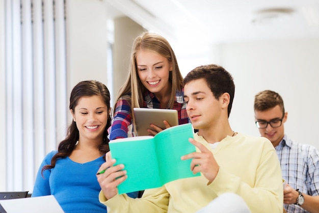 koncepcja edukacji, liceum, pracy zespołowej i ludzi - grupa uśmiechniętych studentów siedzących w sali wykładowej z komputerem typu tablet i notebookami