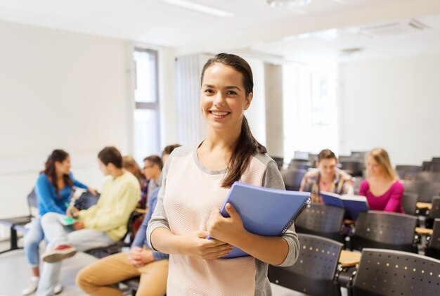 koncepcja edukacji, liceum, pracy zespołowej i ludzi - grupa uśmiechniętych studentów z notatnikami siedząca w sali wykładowej