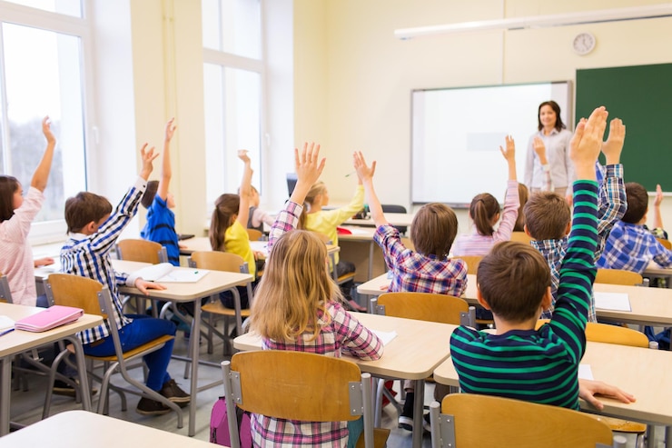Zdjęcie koncepcja edukacji, szkoły podstawowej, uczenia się i ludzi - grupa dzieci w wieku szkolnym z nauczycielem siedzącym w klasie i podnoszącym ręce