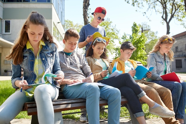 koncepcja edukacji, szkoły średniej i ludzi - grupa nastoletnich uczniów z zeszytami uczącymi się na dziedzińcu kampusu