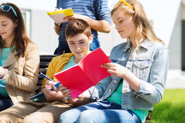 koncepcja edukacji, szkoły średniej i ludzi - grupa szczęśliwych nastoletnich uczniów z zeszytami uczącymi się na dziedzińcu kampusu