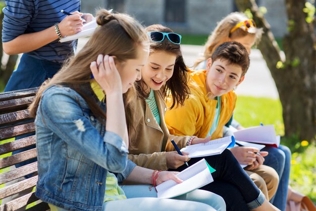 koncepcja edukacji, szkoły średniej i ludzi - grupa szczęśliwych nastoletnich uczniów z zeszytami uczącymi się na dziedzińcu kampusu