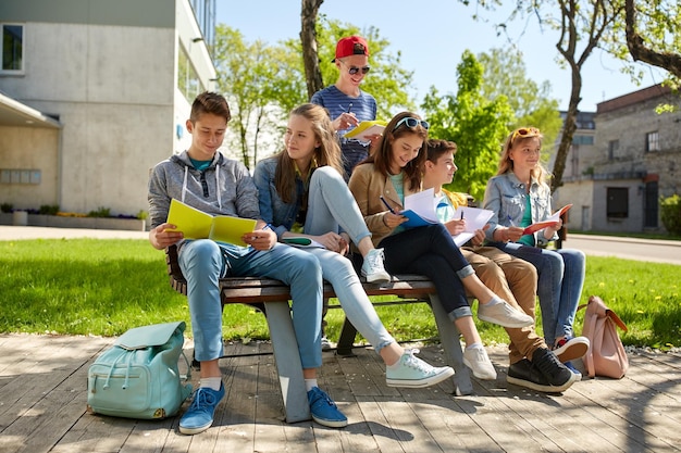 Zdjęcie koncepcja edukacji, szkoły średniej i ludzi - grupa szczęśliwych nastoletnich uczniów z zeszytami uczącymi się na dziedzińcu kampusu