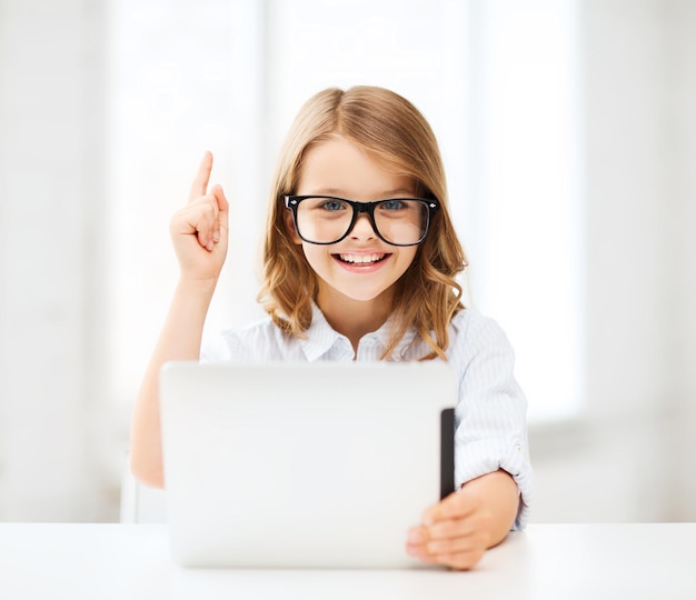 koncepcja edukacji, szkoły, technologii i internetu - mała studentka w czarnych okularach z komputerem typu tablet i palcem w szkole