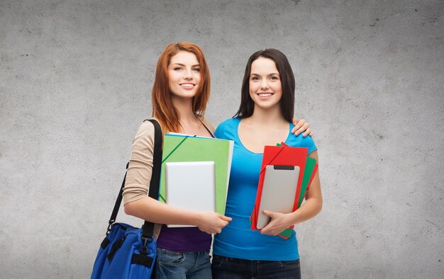 koncepcja edukacji, technologii i ludzi - dwóch uśmiechniętych studentów z torbą, folderami i stojącymi tabletem