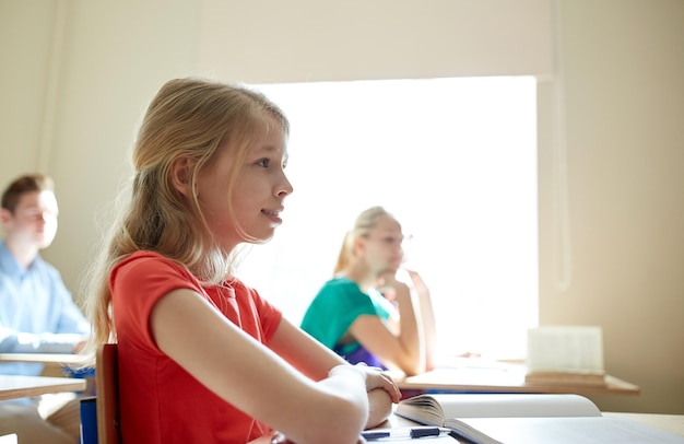 Zdjęcie koncepcja edukacji, uczenia się i ludzi - szczęśliwa uczennica z książką na lekcji w szkole