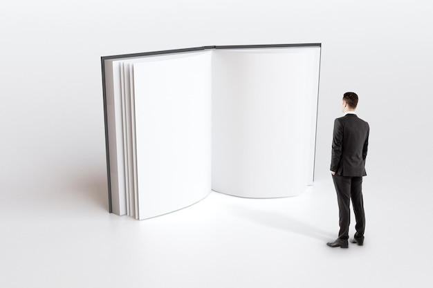 Koncepcja edukacji z biznesmenem patrzącym na puste strony białej księgi makiety