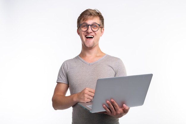 Koncepcja emocji, edukacji i ludzi - młody przystojny mężczyzna, patrząc w laptopa i śmiejąc się
