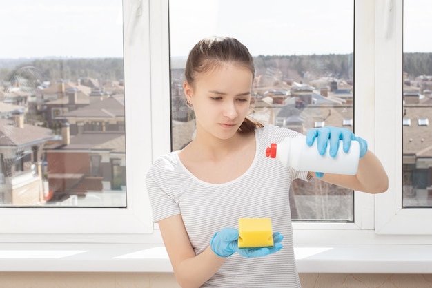 Koncepcja firmy sprzątającej Młoda kobieta wylewa detergent z butelki na gąbkę