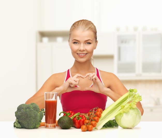 koncepcja fitness, diety i jedzenia - uśmiechnięta kobieta z ekologiczną żywnością pokazującą kształt serca rękami