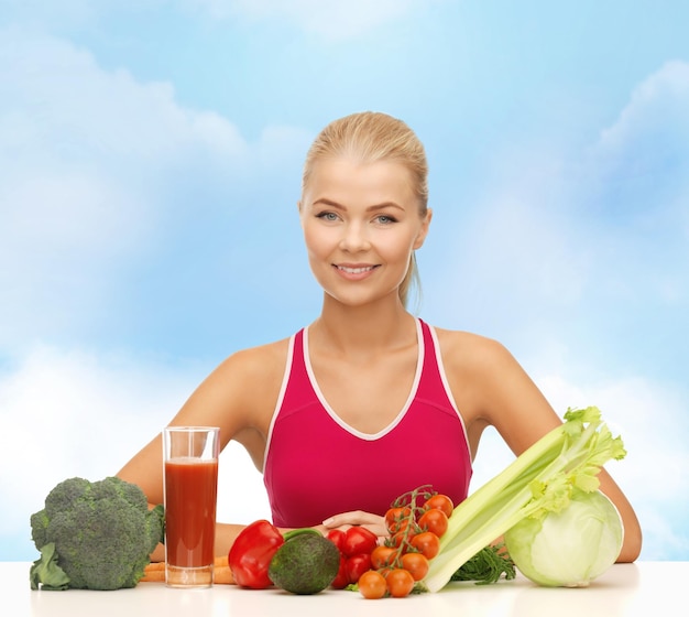 koncepcja fitness, diety i opieki zdrowotnej - uśmiechnięta młoda kobieta z żywnością ekologiczną na stole