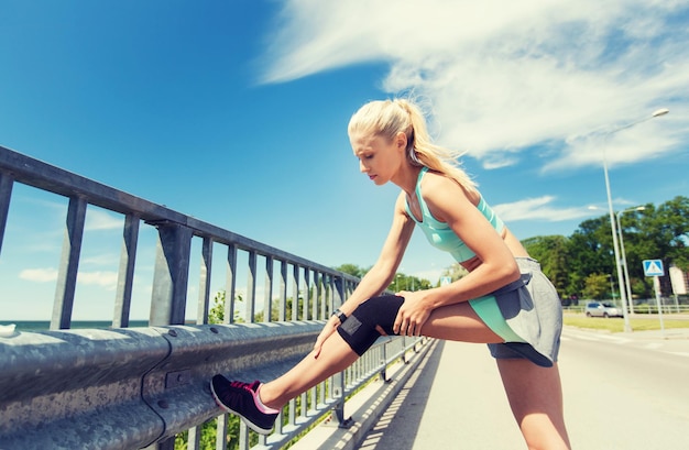 koncepcja fitness, sport, ćwiczenia i zdrowy styl życia - młoda kobieta z uszkodzonym kolanem lub nogą na zewnątrz