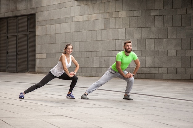 Koncepcja fitness, sport, ćwiczenia, szkolenia i ludzie - para robi triceps dip ćwiczenia na ławce ulicy miasta.