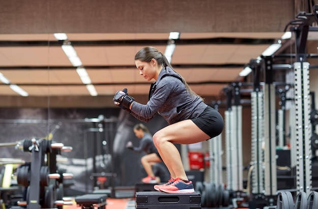 koncepcja fitness, sportu, ćwiczeń i ludzi - kobieta robi przysiady na platformie w siłowni