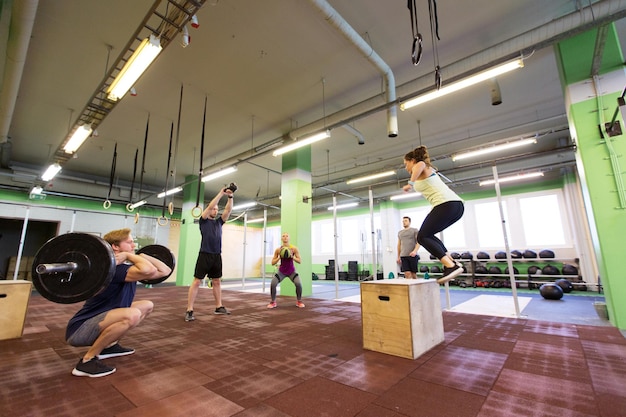 koncepcja fitness, sportu i ćwiczeń - grupa osób trenujących z różnym sprzętem na siłowni