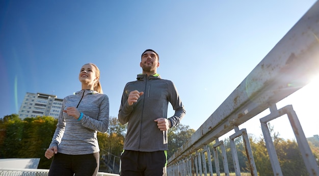 koncepcja fitness, sportu, ludzi i stylu życia - szczęśliwa para biegająca na świeżym powietrzu